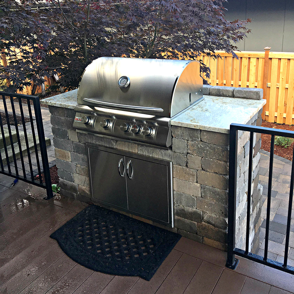 Outdoor kitchen with grill, sink, and pizza oven